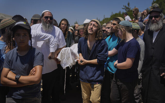 Mourners carry the body of terror victim Nachman Mordoff, 17, during his funeral in the West Bank settlement of Shilo, June 21, 2023 (AP Photo/Ohad Zwigenberg)