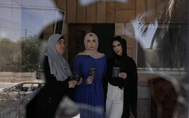 Palestinian-Americans Olfat Abdel Aziz, left, and her daughters Nur, center, and Amal, right, pose for a portrait with their US passports in their damaged home in the West Bank town of Turmus Ayya, days after a rampage by settlers, Friday, June 23, 2023.(AP Photo/Majdi Mohammed)