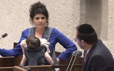 Screen capture from video of National Unity MK Sharren Haskel, left, wearing her baby daughter in a sling, and Deputy Knesset Speaker of Shas, Uriel Buso, in the Knesset, June 27, 2023. (Twitter. Used in accordance with Clause 27a of the Copyright Law)