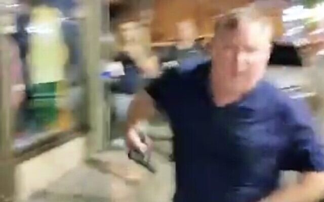 Screen capture from video of a man pulling out a pistol during a confrontation with an anti-government protester in Petah Tikva, JUne 26, 2023. (Twitter. Used in accordance with Clause 27a of the Copyright Law)