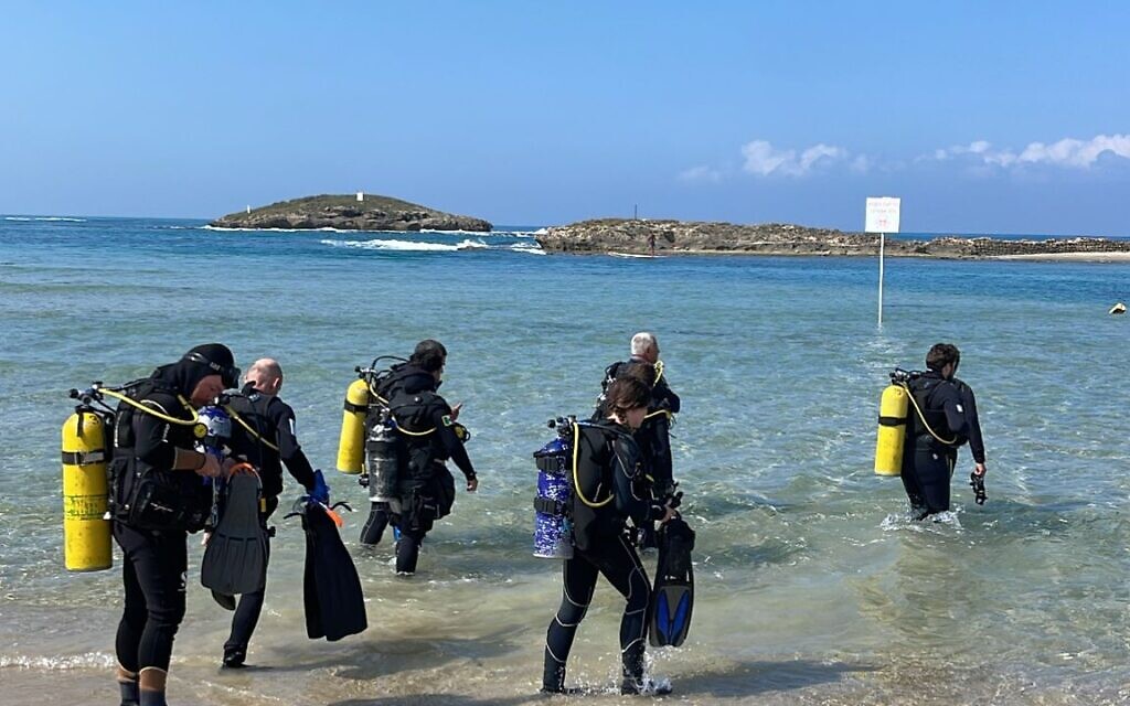 Students, volunteers, and professors from Haifa University's marine archaeology masters program enter the water for an excavation shift on May 9, 2023 at Dor Beach. (Melanie Lidman/Times of Israel)