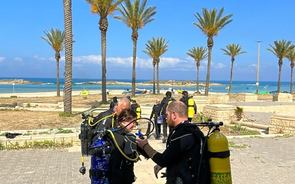 Haifa University students do an equipment check before starting a marine archaeology dive at Dor Beach on May 9, 2023. (Melanie Lidman/Times of Israel)