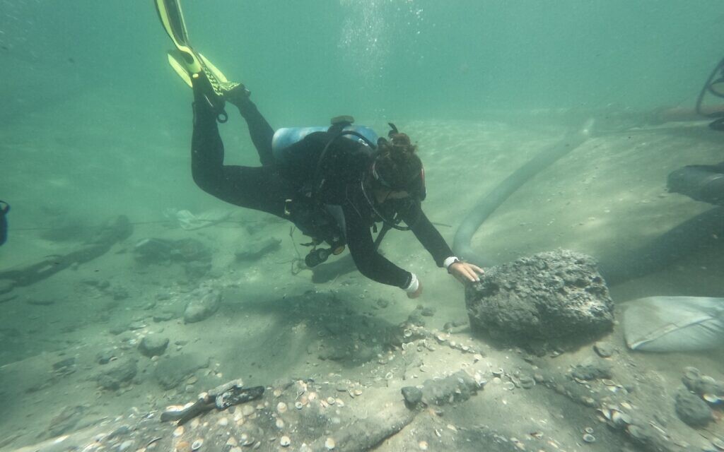 An archaeologist explores remains of cargo from a shipwreck that likely occurred between 1000 BCE and 500 BCE at Dor Beach, during the May 2023 excavation season. (courtesy Department of Maritime Civilizations/University of Haifa)