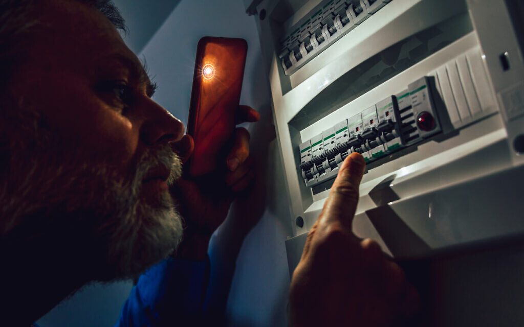 A man checks a fuse box during a power outage. (Jovanmandic, iStock at Getty Images)