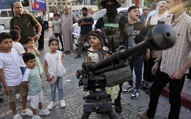 Palestinians pose for souvenir pictures with weapons during an exhibition by Gaza's Hamas terrorist rulers in Gaza City on June 30, 2023. (Mohammed ABED / AFP)