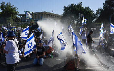 Members of Israel's security forces use a water cannon to disperse demonstrators blocking an entrance to the Knesset in Jerusalem on July 24, 2023. (Menahem Kahana/AFP)