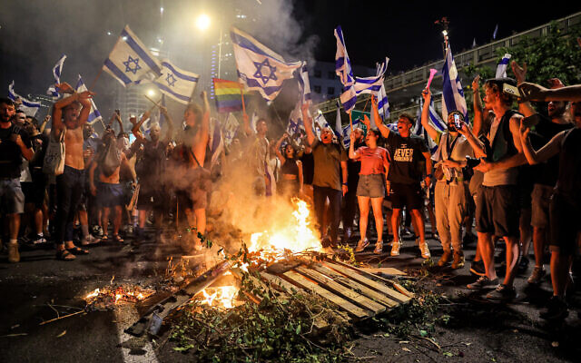 Demonstrators gather at a bonfire as they block the Ayalon Highway during a protest rally against the Israeli government's judicial reform, in Tel Aviv on July 24, 2023. (Jack Guez / AFP)