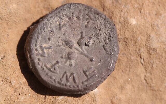 The 2,000-year-old coin as it was discovered in a cave near Ein Gedi, with three pomegranates and the words "Holy Jerusalem" in ancient script. (Emil Aladjem/IAA)