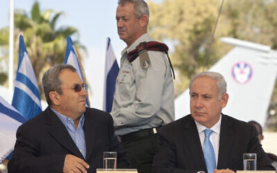 Prime Minister Benjamin Netanyahu, right, sits with former prime minister Ehud Barak, left, as former IDF chief of staff Lt. Gen. Benny Gantz walks during a press conference at the Tel Nof Air Force base, October 18, 2011. (AP Photo/Sebastian Scheiner)