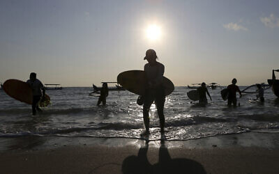 Surfers carry their board during the sunset at Kuta beach in Bali, Indonesia on June 24, 2023. (Firdia Lisnawati/AP)