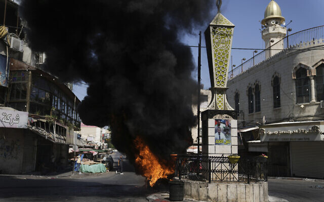 Tires burn during an Israeli military raid in the Jenin refugee camp in the West Bank, July 3, 2023 (AP Photo/Nasser Nasser)