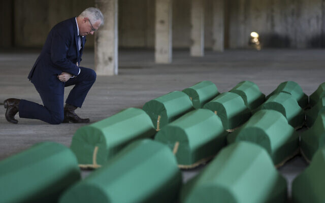 United States Ambassador to Bosnia and Herzegovina Michael J. Murphy kneels next to the coffins containing remains of 30 newly identified victims of the Srebrenica Genocide in Potocari, Bosnia, July 10, 2023. (AP/Armin Durgut)
