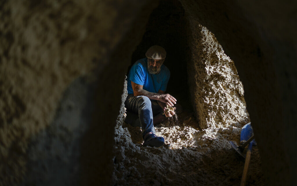 Nissim Kahlon works in a chamber in his home chiseled out of the sandstone cliffs overlooking the Mediterranean Sea in Herzliya, June 28, 2023. (AP Photo/Ariel Schalit)