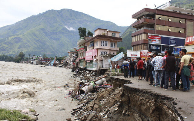 People stand by a road washed away by the River Beas swollen due to heavy rains in Kullu District, Himachal Pradesh, India, July 11, 2023. (AP Photo/Aqil Khan)