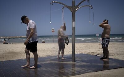 Men shower at a public beach as they take refuge from a summer heat wave in Tel Aviv on Thursday, July 13, 2023. (AP Photo/Maya Alleruzzo)