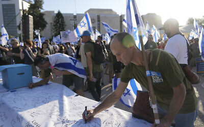 Israeli military reservists sign a declaration of refusal to report for duty to protest against plans by Prime Minister Benjamin Netanyahu's government to overhaul the judicial system, in Tel Aviv, Israel, July 19, 2023. (AP Photo/Ohad Zwigenberg)