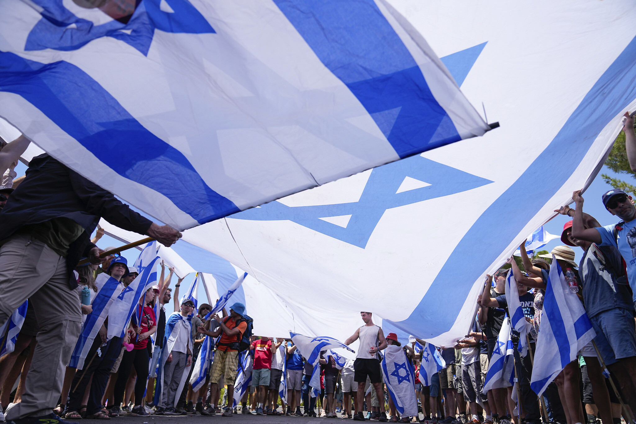 Demonstrators wave large Israeli flags during a protest against the Netanyahu government's overhaul of the judicial system, outside the Knesset in Jerusalem, on Monday, July 24, 2023, as parliament passed the 'reasonableness' law. (AP/Ohad Zwigenberg)