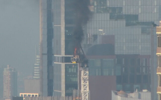 Emergency responders battle flames as a large construction crane caught fire in Manhattan on Wednesday, July 26, 2023 in New York.   The crane caught fire and its arm hit a building as it crashed to the street below. (WABC via AP)