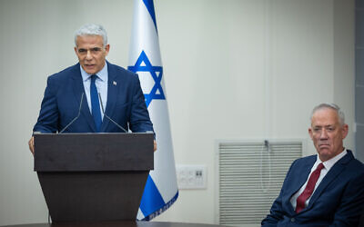 Yesh Atid head Yair Lapid speaks during a press conference next to Benny Gantz, seated, on June 14, 2023. (Yonatan Sindel/Flash90)