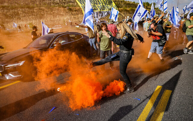 Demonstrators block a road and clash with police during a protest against the judicial overhaul on Route 1, near Ein Hemed, July 11, 2023. (Chaim Goldberg/Flash90)
