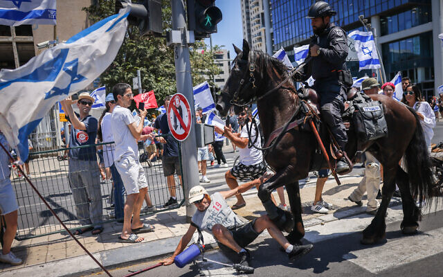 A horse tramples a man at a protest against the judicial overhaul in Tel Aviv, July 11, 2023 (Chaim Goldberg/Flash90)