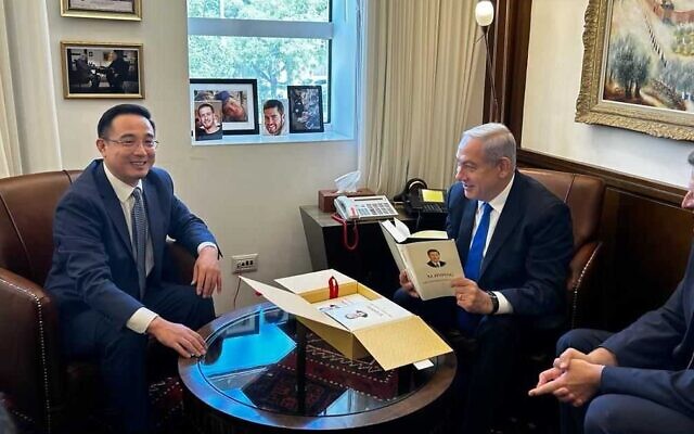 In this handout photo, Prime Minister Benjamin Netanyahu (right) holds a autographed copy of Chinese leader Xi Jinping's book that was given to him by China's Ambassador to Israel Cai Run, at the Prime Minister's Office in Jerusalem, July 26, 2023 (Courtesy)