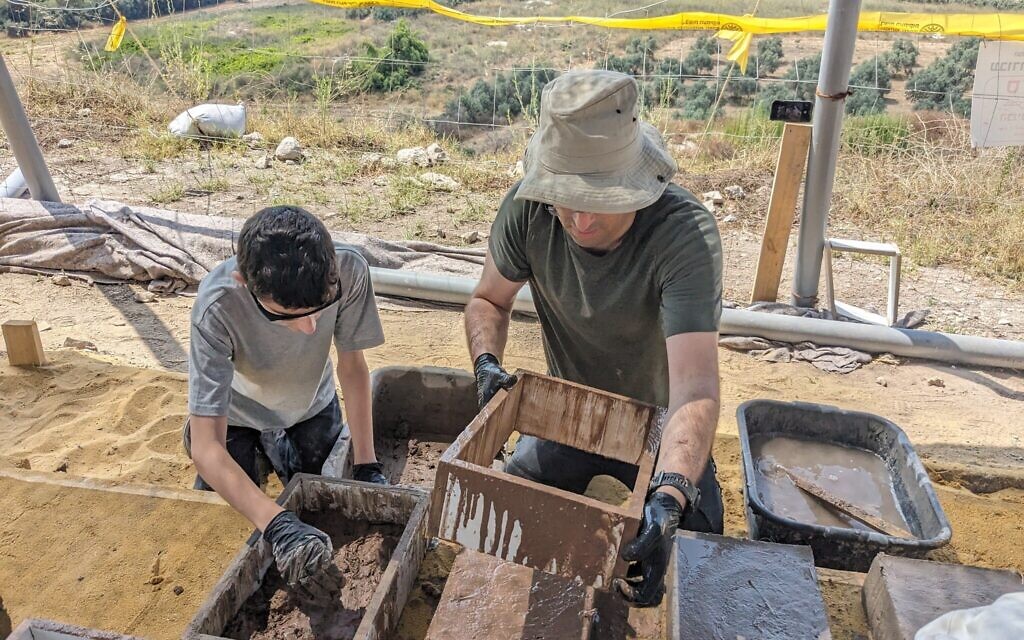 Father and son duo Yonatan (right) and Lahav Drori from Tel Aviv make bricks from molds at Tel Gezer on July 6, 2023. (Melanie Lidman/Times of Israel)