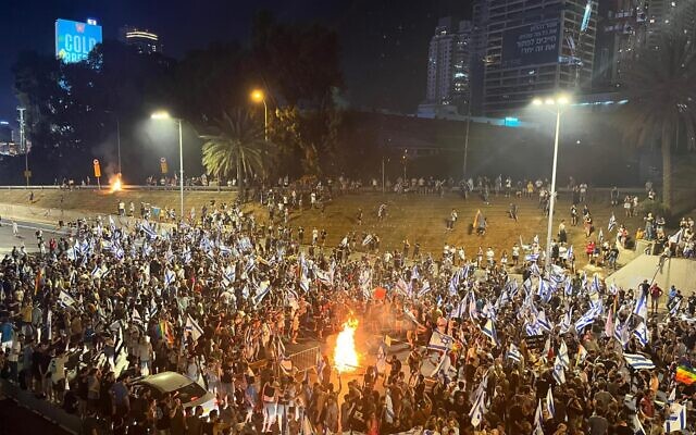 Demonstrators gather at a bonfire during a protest rally against the government's judicial overhaul on Tel Aviv's Ayalon highway on July 24, 2023. (Naomi Lanzkron/ Times of Israel)