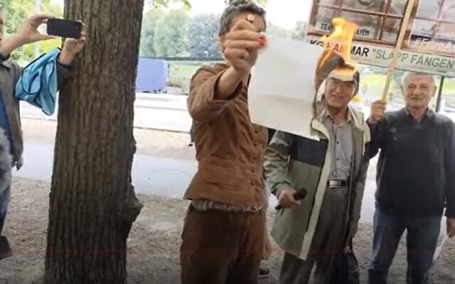 A woman burns a piece of paper in front of the Israeli Embassy in Stockholm on July 28, 2023. (Screen capture/Hedlund Media TV, used in accordance with clause 27a of the copyright law)