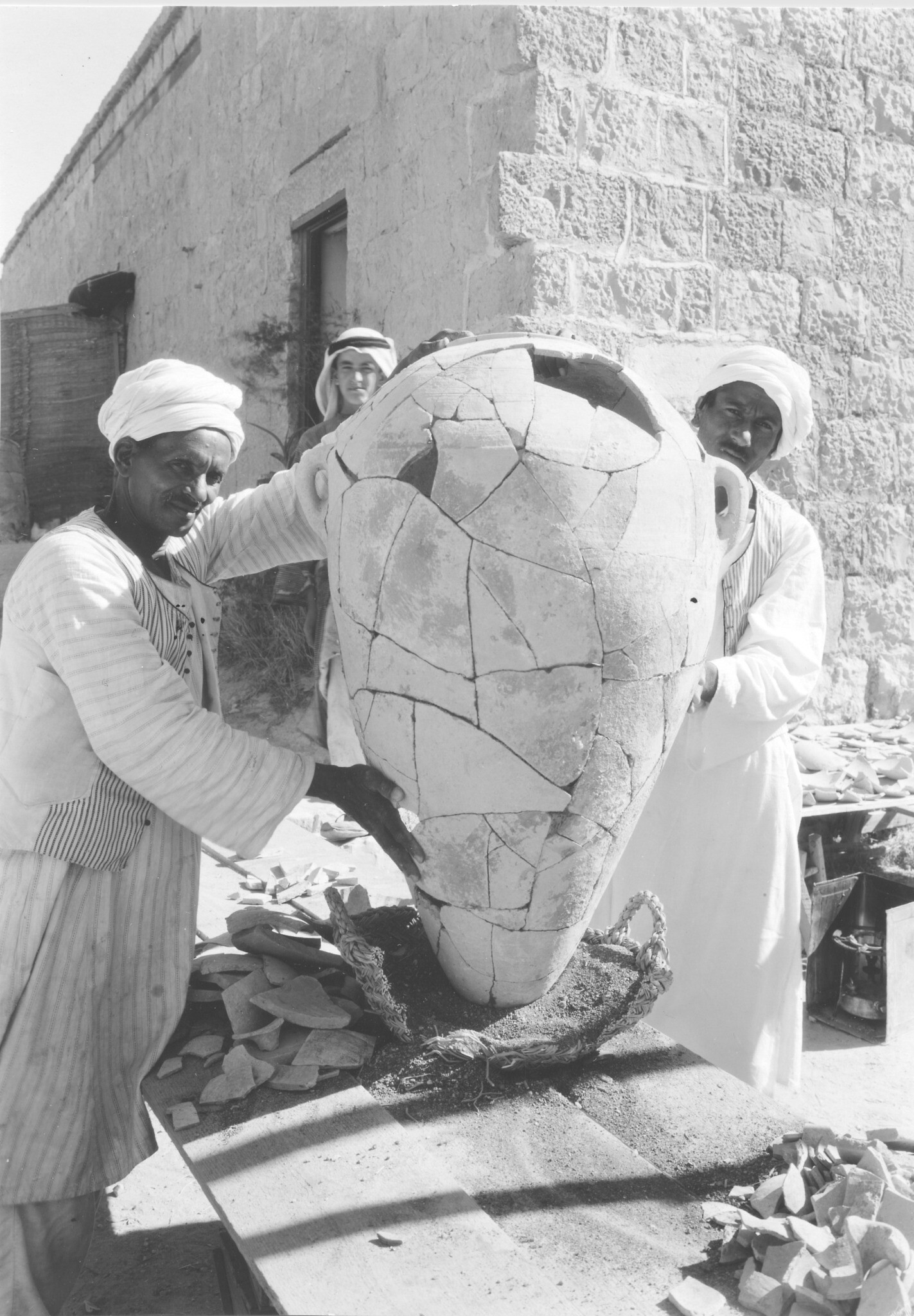 An excavated storage jar displayed on the terrace of the dig house after restoration by the reises, led by Reis Mahmoud Abdel Mazim Tantawi (right), the lead pot-mender in the 1932 and 1935 seasons. (Courtesy of the Badè Museum/Pacific School of Religion)