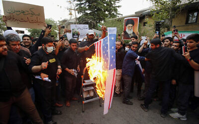 Iranian students burn a US flag during a demonstration denouncing the burning in Sweden of the Quran, Islam's holy book, in front of Swedish embassy in Tehran on July 21, 2023. (AFP)