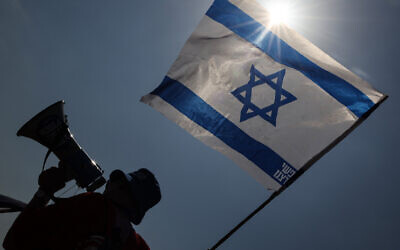 File: An activist against the government's judicial overhaul waves a national flag during a demonstration in Petah Tikva near Tel Aviv on August 17, 2023. (Jack Guez/AFP)