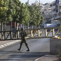 An Israeli soldier mans a checkpoint at the closed-off southern entrance to the southern West Bank city of Hebron, on August 22, 2023, a day after a deadly terror shooting in the area. (Hazem Bader/AFP)