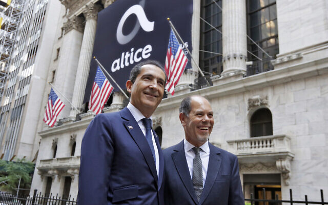 Altice founder Patrick Drahi, left, and co-founder Armando Pereira pose for photos outside the New York Stock Exchange, before the company's IPO, June 22, 2017. (Richard Drew/AP)