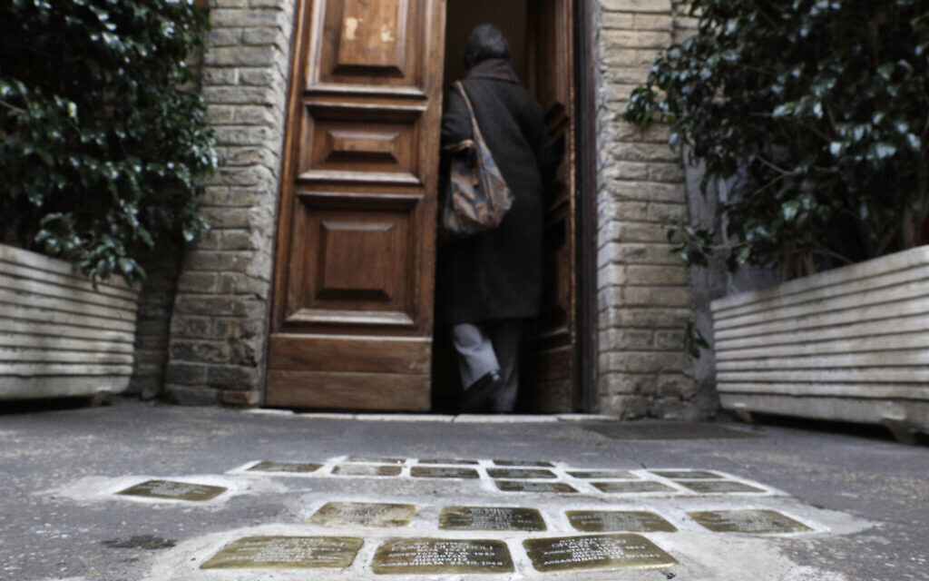 Illustrative: A woman enters a building where stumbling stones, engraved with names of Jews killed by the Nazis, are seen in front of the entrance, in Rome's Ghetto Jewish neighborhood, January 27, 2021. (AP Photo/Gregorio Borgia)
