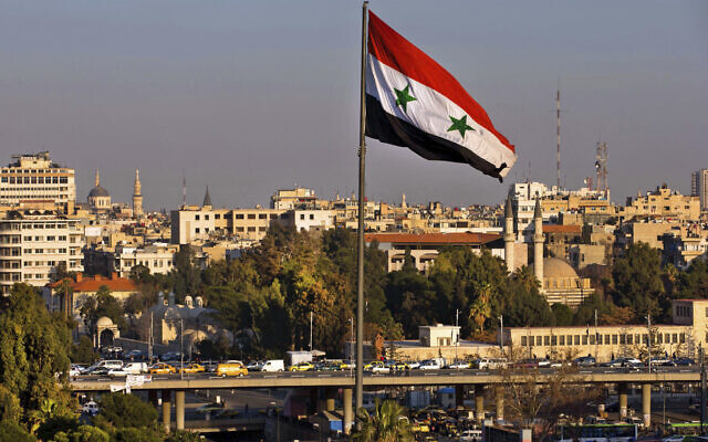 Illustrative: A Syrian national flag waves as vehicles move on a bridge during rush hour, in Damascus, Syria, on Feb. 28, 2016. (Hassan Ammar/AP)