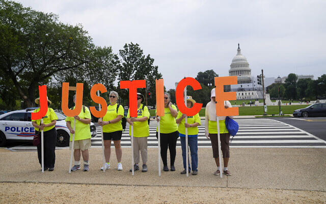 Protesters hold signs that spell JUSTICE with the US Capitol in the background, Thursday, August 3, 2023, in Washington. Former US president Donald Trump is due in federal court Thursday to answer to charges that he sought to overturn the results of the 2020 presidential election. (AP Photo/Jess Rapfogel)