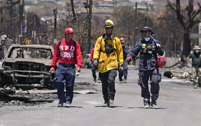 Members of a search-and-rescue team walk along a street, August 12, 2023, in Lahaina, Hawaii, following heavy damage caused by wildfire. (AP Photo/Rick Bowmer)