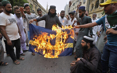Supporters of a radical Islamist party 'Tehreek-e-Labaik Pakistan' burn a representation of a Swedish flag during a rally to denounce burning of Islam's holy book Quran, in Karachi, Pakistan, on July 7, 2023. (Fareed Khan/AP)