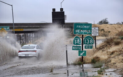 A vehicle drives through a flooded freeway entrance in Palmdale, Calif. as a tropical storm moves into the area on Sunday, Aug. 20, 2023. (AP Photo/Richard Vogel)