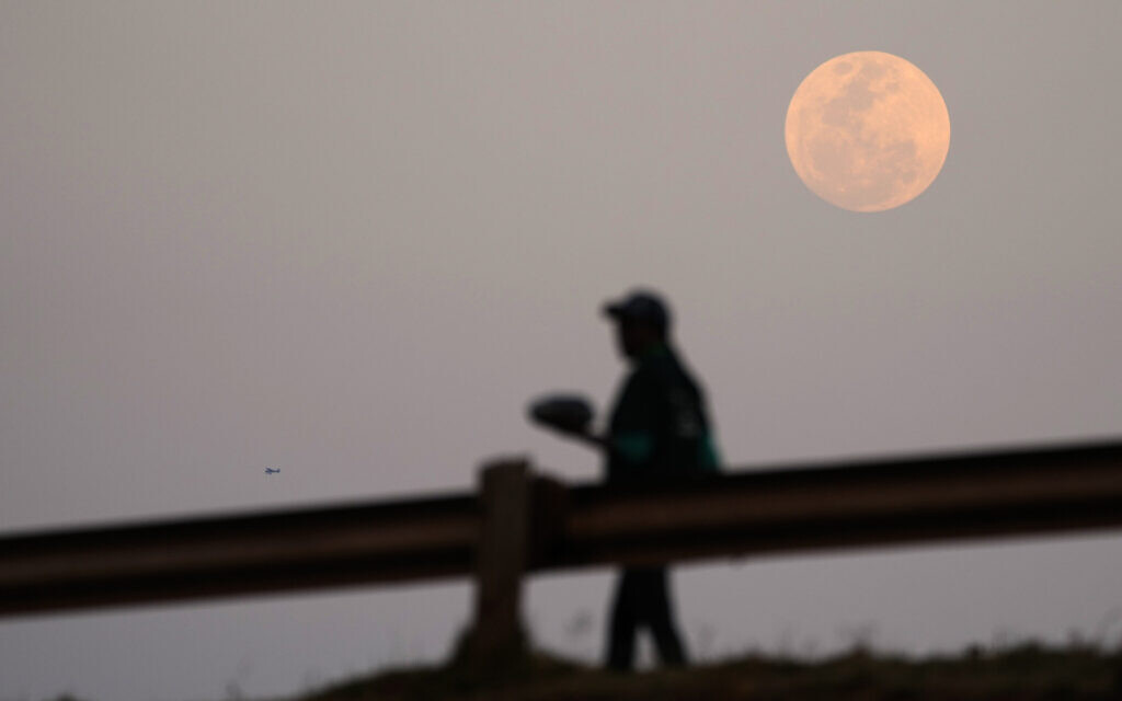 A supermoon is seen on the sky as a woman walks on the street, in Vosloorus, east of Johannesburg, South Africa, August 30, 2023. (Themba Hadebe/AP)