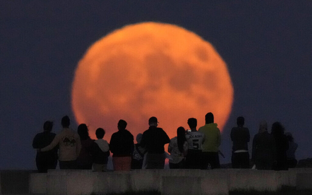 A rare Blue Supermoon rises over Lake Michigan as spectators watch from Chicago's 31st Street beach August 30, 2023. (Charles Rex Arbogast/AP)
