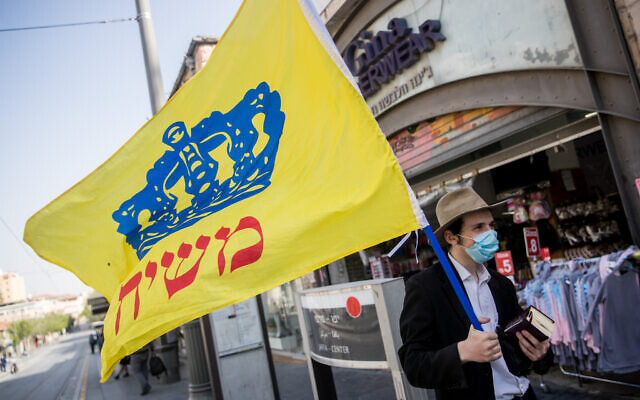 Illustrative: A man holds a Chabad flag on Jaffa street in downtown Jerusalem on April 20, 2020. (Yonatan Sindel/Flash90)