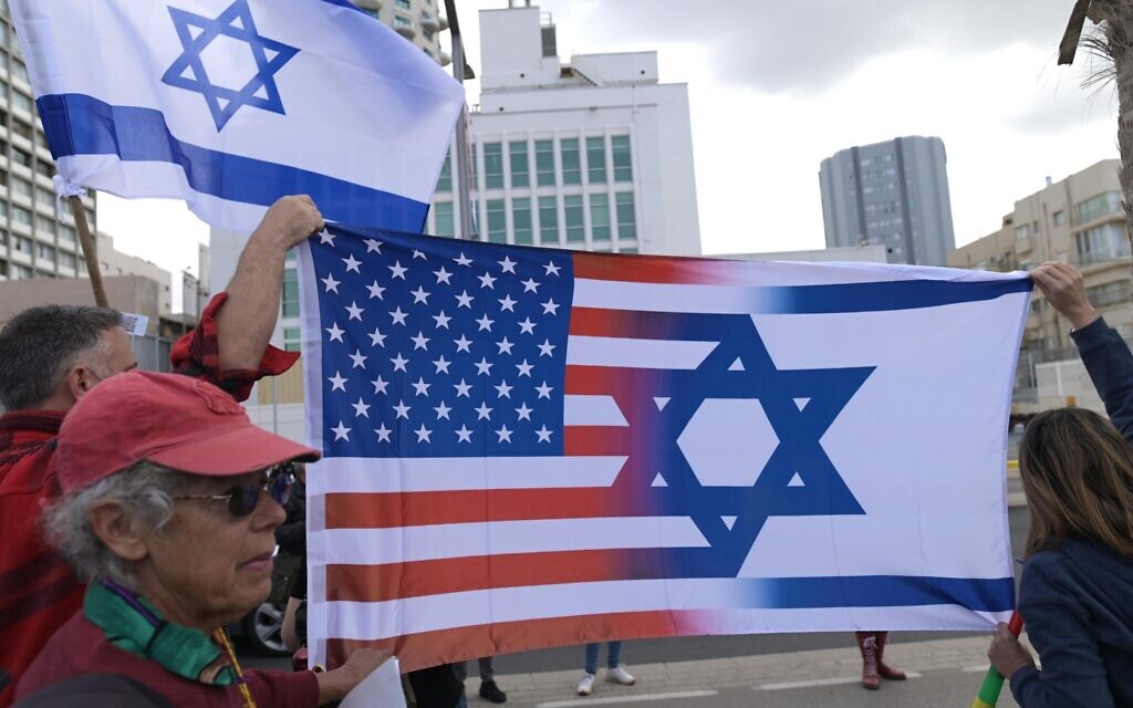 Israelis wave Israeli and American flags as they protest the coalition's judicial overhaul legislation, outside the US consulate in Tel Aviv, March 7, 2023. (Tomer Neuberg/Flash90)