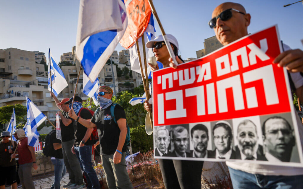 Activists protest against the government's planned judicial overhaul, outside the ultraconservative Har Hamor Yeshiva in the Jerusalem neighborhood of Har Homa, July 5, 2023. The sign, featuring leading members of the government, states 'You are the messianics of the destruction.' (Chaim Goldberg/Flash90)