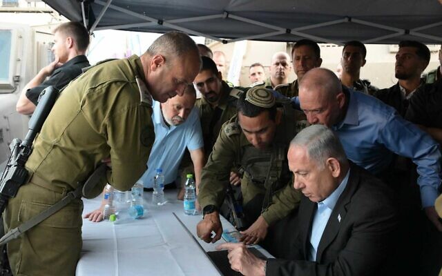 Prime Minister Benjamin Netanyahu and Defense Minister Yoav Gallant (right) are briefed near the scene of a terror shooting near the West Bank city of Hebron, August 21, 2023. (Amos Ben Gershom/GPO)
