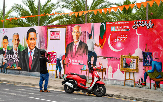 A commuter takes pictures with his mobile phone of a decorated wall along a street ahead of presidential elections in The Maldives, in the capital Male on September 6, 2023. (Mohamed Afrah / AFP)