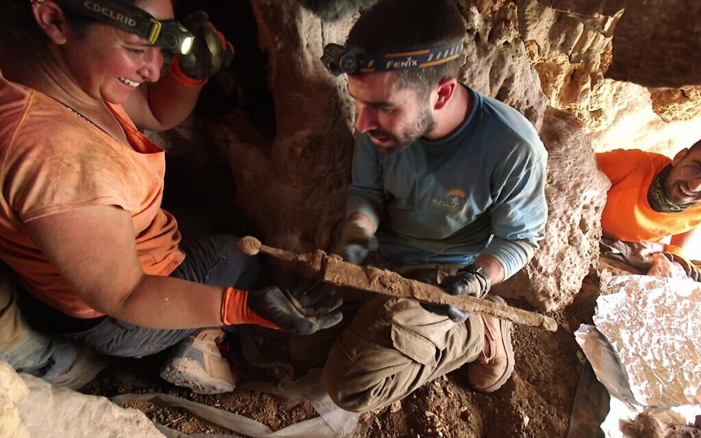 Archaeologists remove the swords from the rock crevice where they were hidden some 1,900 years ago in a cave in the Judean Desert. (Emil Aladjem/IAA)