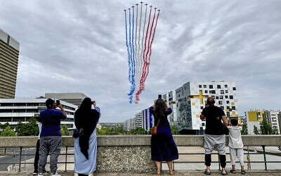 FILE - Residents watch jets from the Patrouille de France flying over Paris suburb Nanterre during the Bastille Day military parade on July 14, 2023 in Nanterre (AP Photo/Youcef Bounab, File)