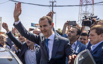 Syrian President Bashar Assad, center, waves to his supporters at a polling station during the Presidential elections in the town of Douma, in the eastern Ghouta region, near the Syrian capital Damascus, Syria, May 26, 2021. (AP Photo/Hassan Ammar, File)